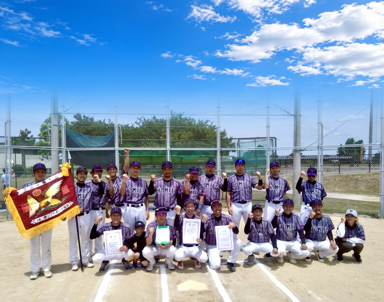 グラウンドで優勝旗と表彰状を囲む堺ホーミーズのメンバー